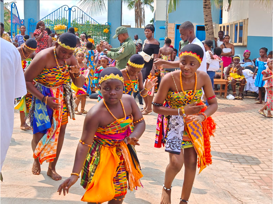 Students performing a traditional Asante dance in colourful kente cloth.